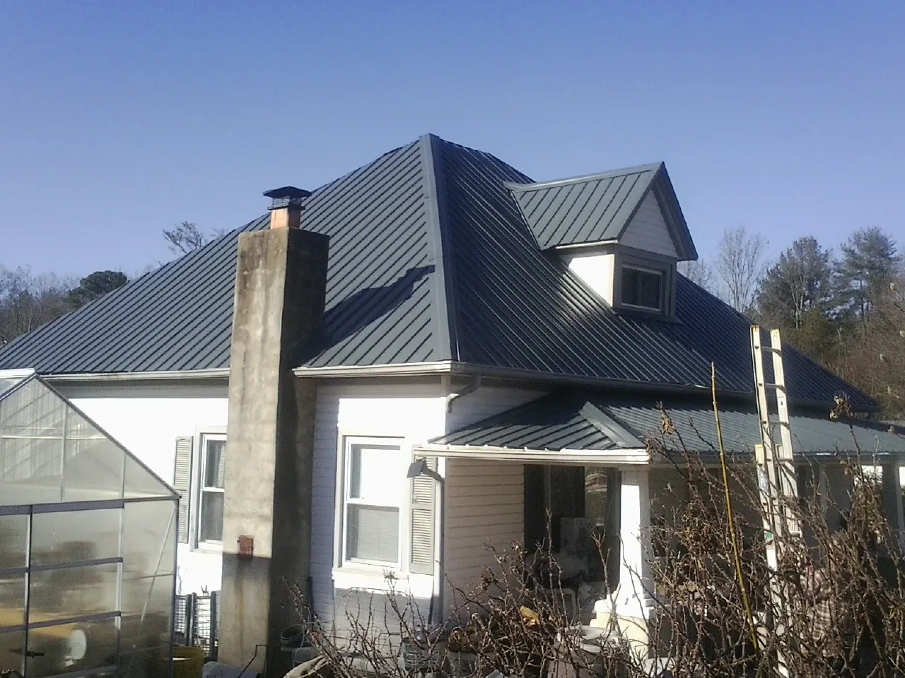 Dark blue standing seam metal roof on a white farmhouse with dormer — Slate & Tile Roof Repair by Roofing Brothers in Daly City