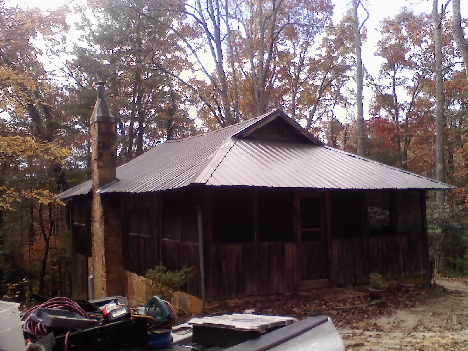 Brown metal hip roof on an old cabin with a stone chimney in Daly City