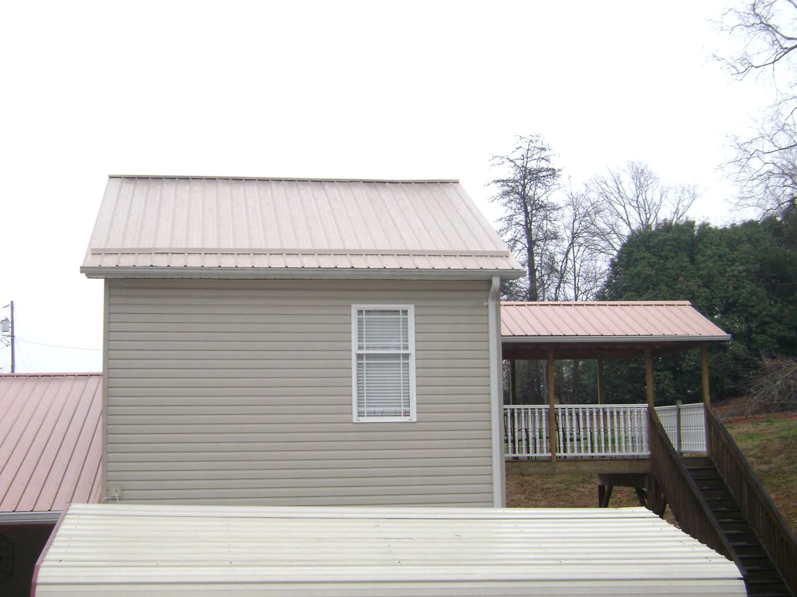 Tan metal roofs on a two story addition and attached porch, from a Roof Replacement job in Daly City
