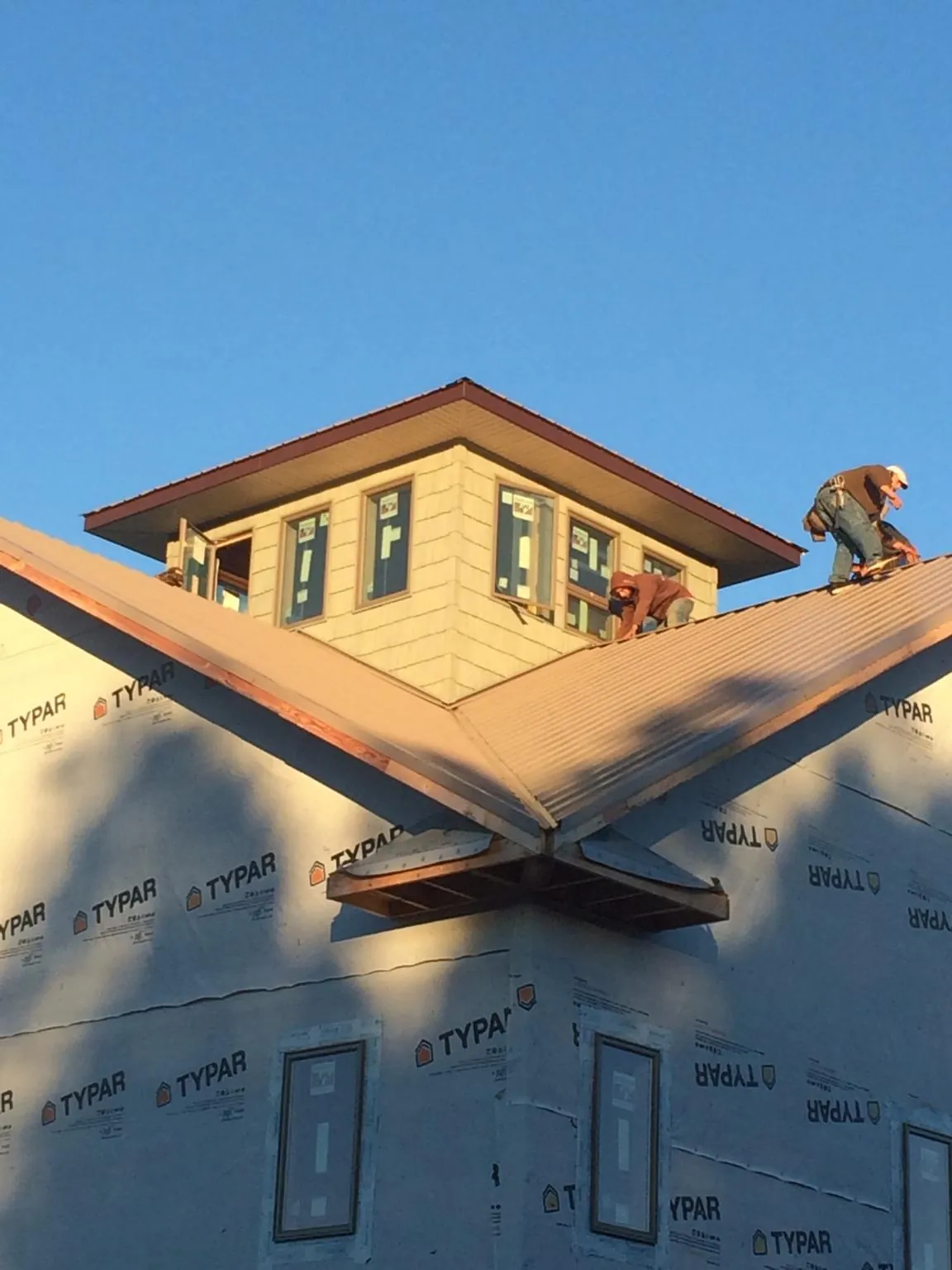 Roofers working around a rooftop cupola on a new metal roof at sunset — Roof Waterproofing in Daly City by Roofing Brothers